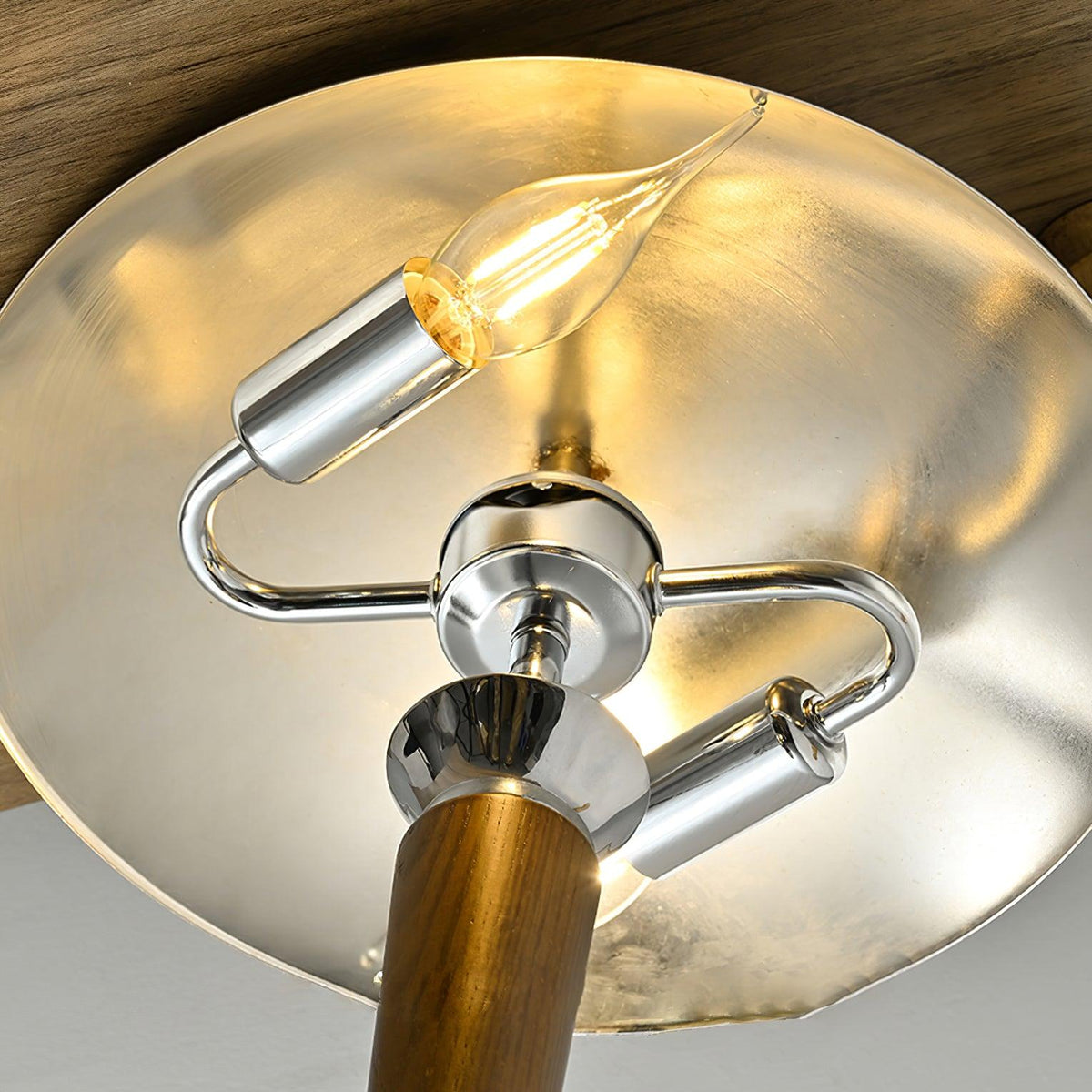 Looking up inside the chrome shade of this Clérachic floor lamp, a candle-style bulb on chrome arms below a silvered dome.