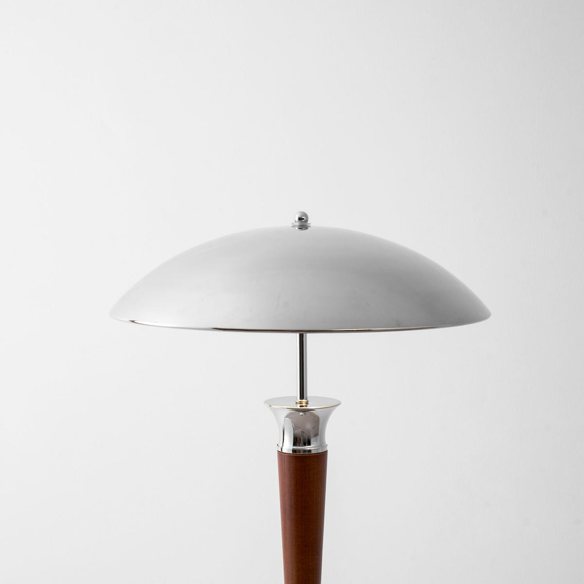 Close view of the chrome dome shade on this Clérachic floor lamp, above a walnut stem and a chrome collar.