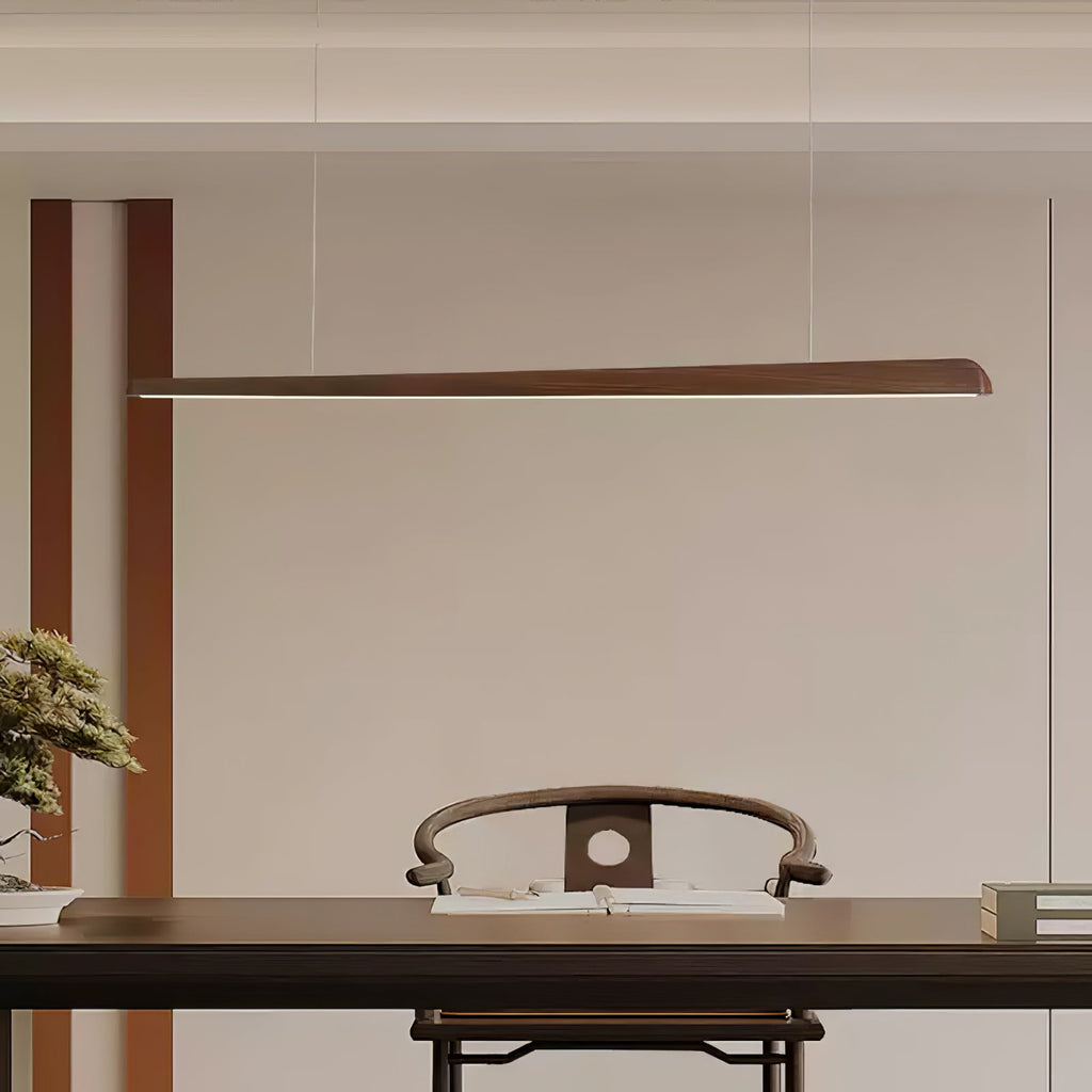 Slender walnut bar pendant hung high on thin wires above a dark table and a carved wooden chair, from Clérachic.