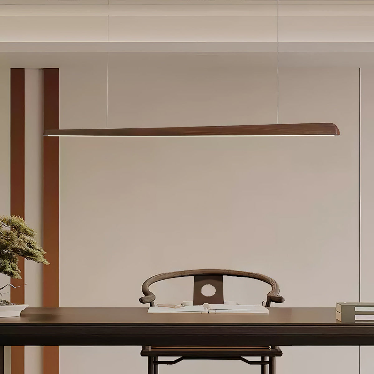 Slender walnut bar pendant hung high on thin wires above a dark table and a carved wooden chair, from Clérachic.