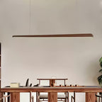 Clérachic walnut bar pendant above a tea table set with small cups, seen straight on against a warm grey wall.