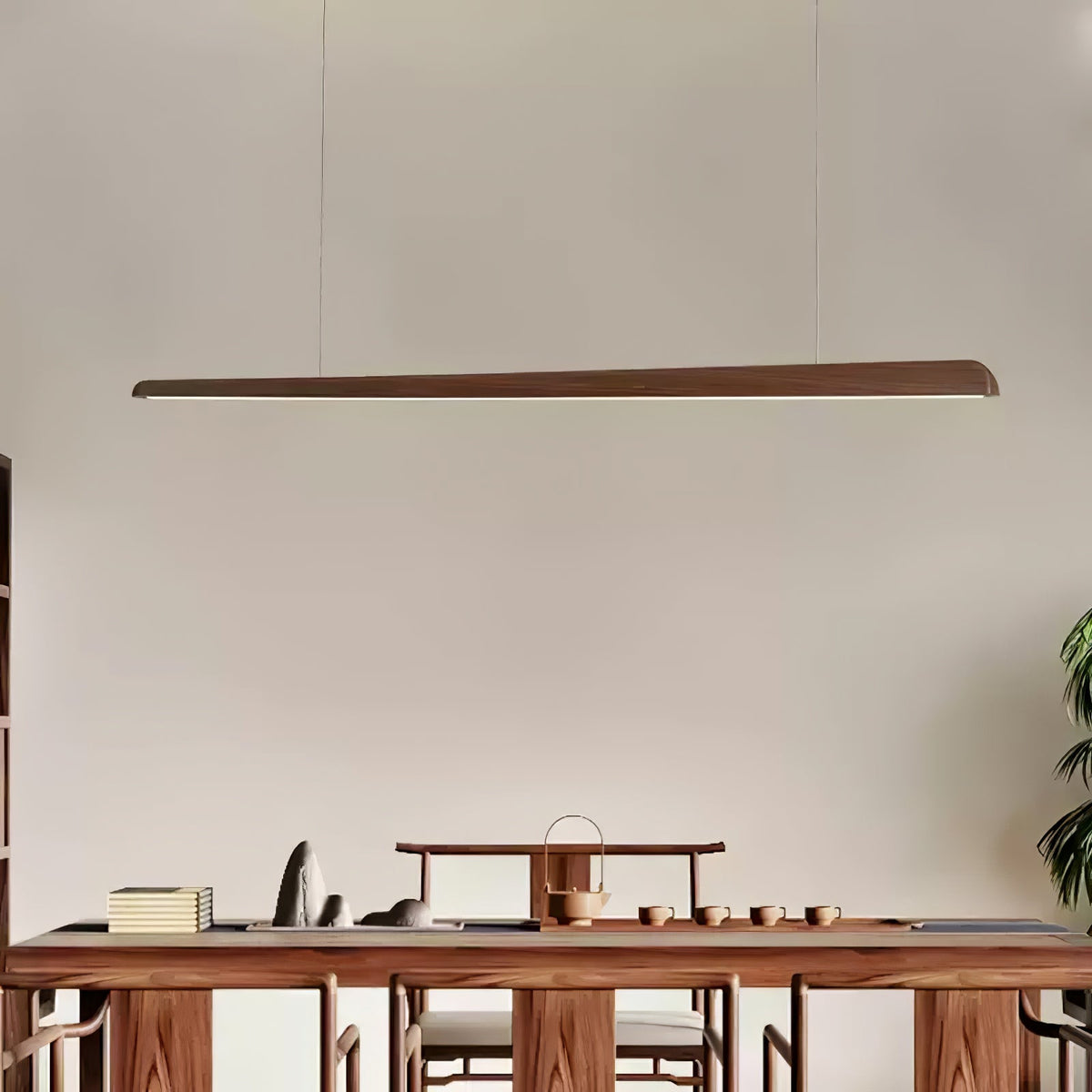 Clérachic walnut bar pendant above a tea table set with small cups, seen straight on against a warm grey wall.