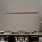 Walnut bar pendant with a pale light strip along its underside, hung above a tea table with a ceramic vase, from Clérachic.