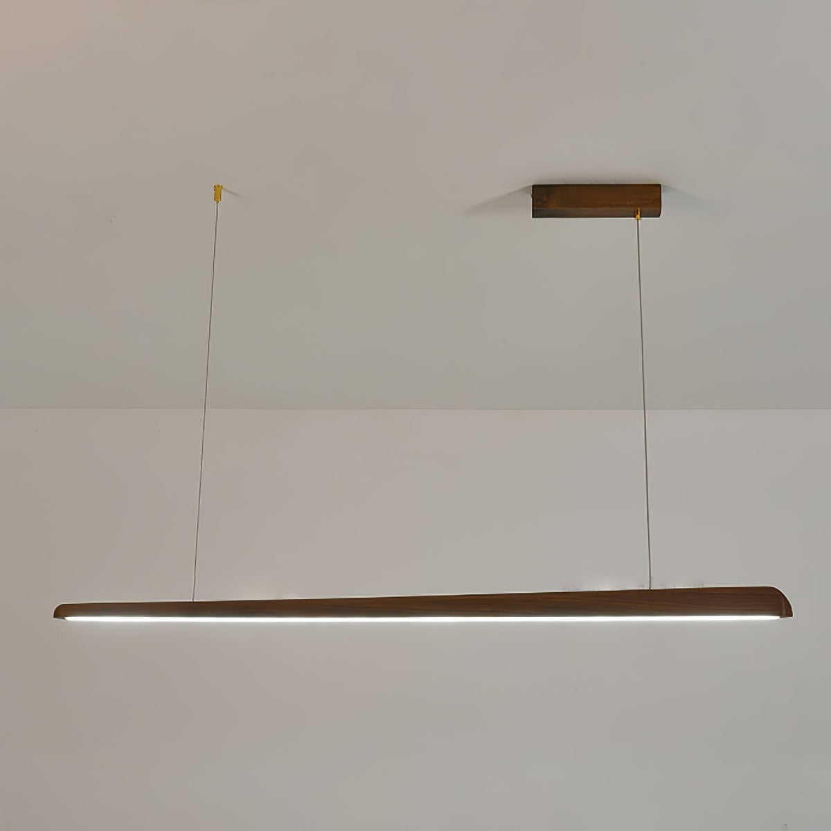 Walnut bar pendant on two thin wires from a wooden ceiling plate, glowing with a cool white light, from Clérachic.