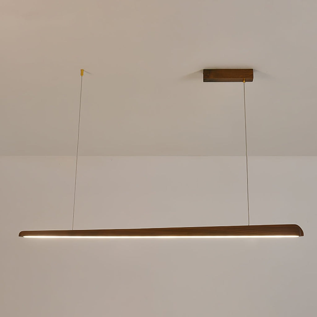 Walnut bar pendant on two thin wires, lit with a neutral white strip along its underside, from Clérachic.
