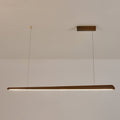 Walnut bar pendant on two thin wires, lit with a neutral white strip along its underside, from Clérachic.