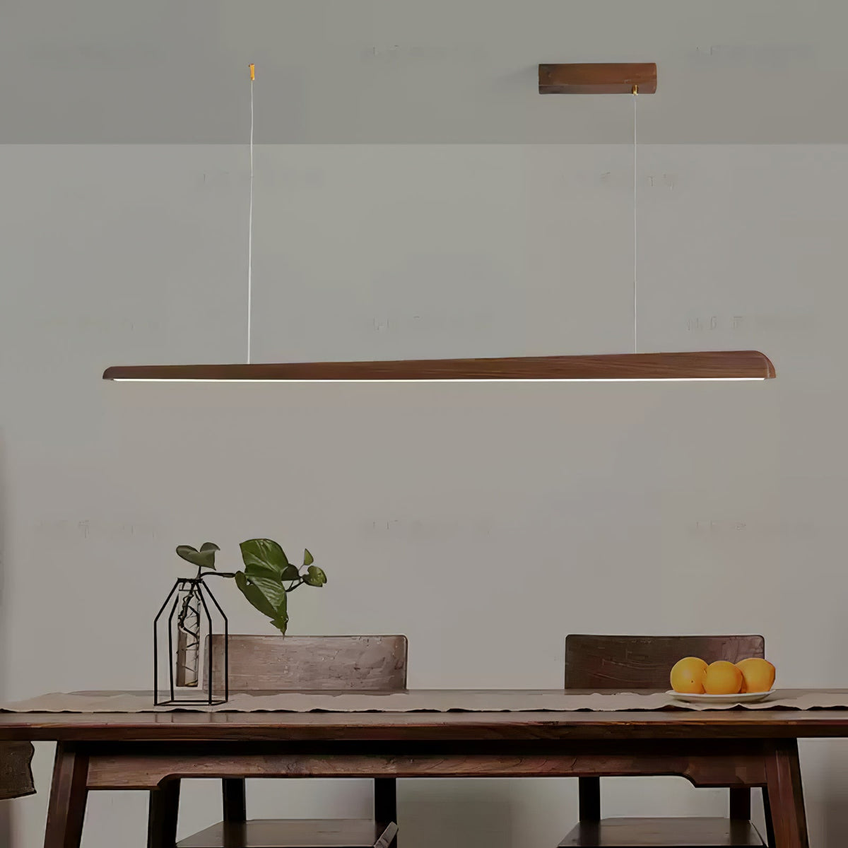 Walnut bar pendant above a wooden table with a glass vase and a plate of oranges, light glowing below, from Clérachic.