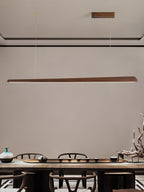 Clérachic walnut bar pendant hung on thin wires in a tall room, above a tea table with ceramics and a driftwood piece.