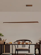 Walnut bar pendant hung above a dark tea table, with an armchair and a small plant behind it, from Clérachic.