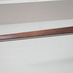 Close view of the walnut grain and the pale diffuser strip along the underside of this Clérachic bar pendant.