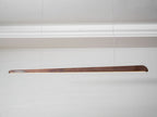 Walnut bar pendant on two thin wires beneath a white cornice, seen from a low angle, from Clérachic.