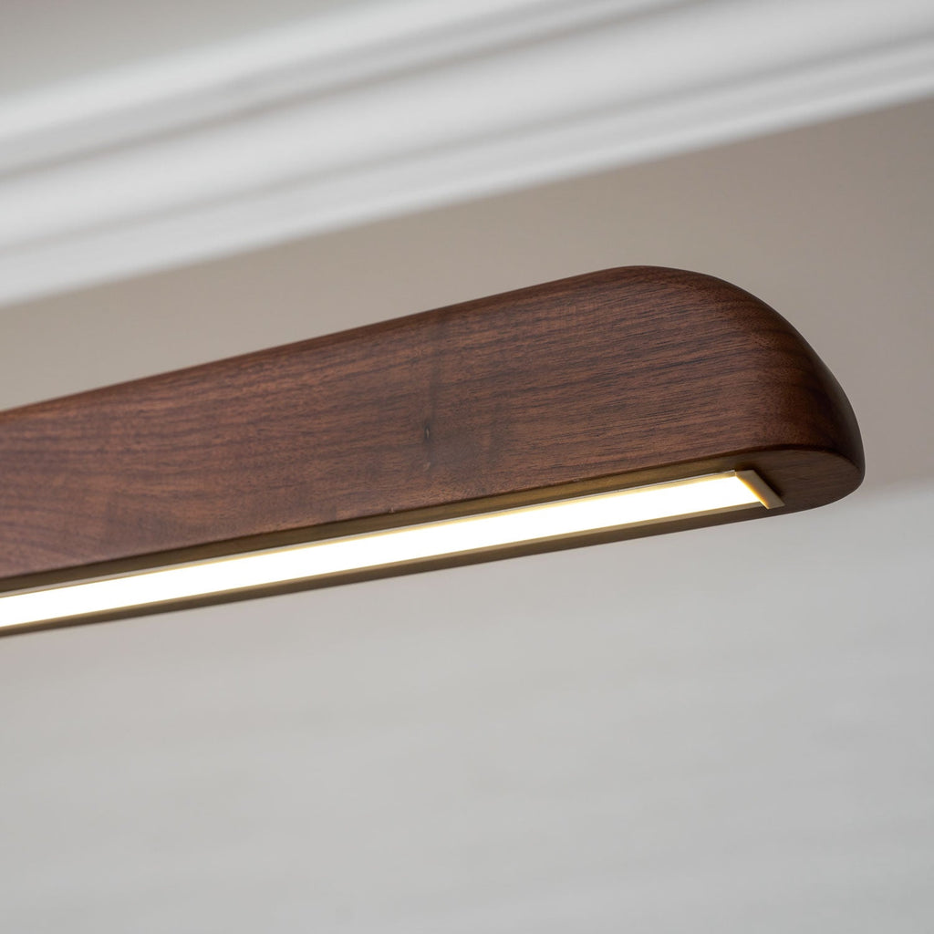 Close view of the rounded walnut end with its warm glowing light strip, on this Clérachic pendant.