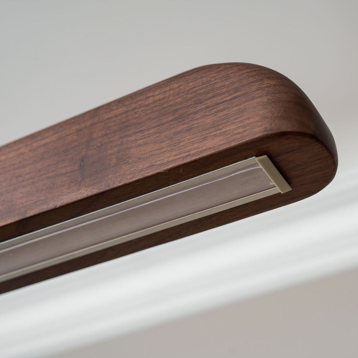 Underside view of the walnut end cap and the unlit diffuser channel on this Clérachic bar pendant.