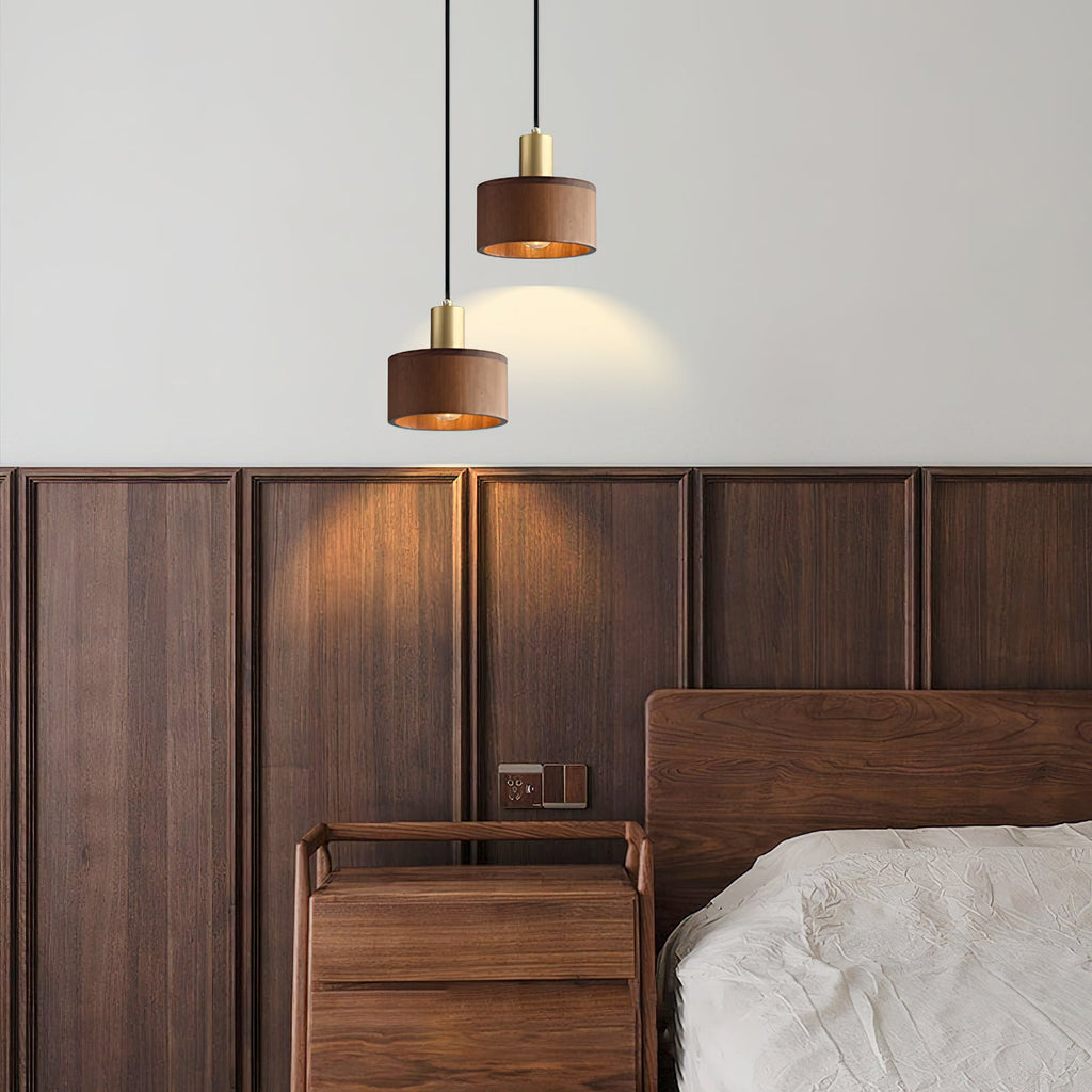 Two of these Clérachic walnut pendants hang at different heights beside a panelled walnut headboard wall, casting a warm pool of light.