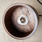 Looking up into this Clérachic pendant from below: a bare filament bulb sits on a round walnut disc inside the shade.