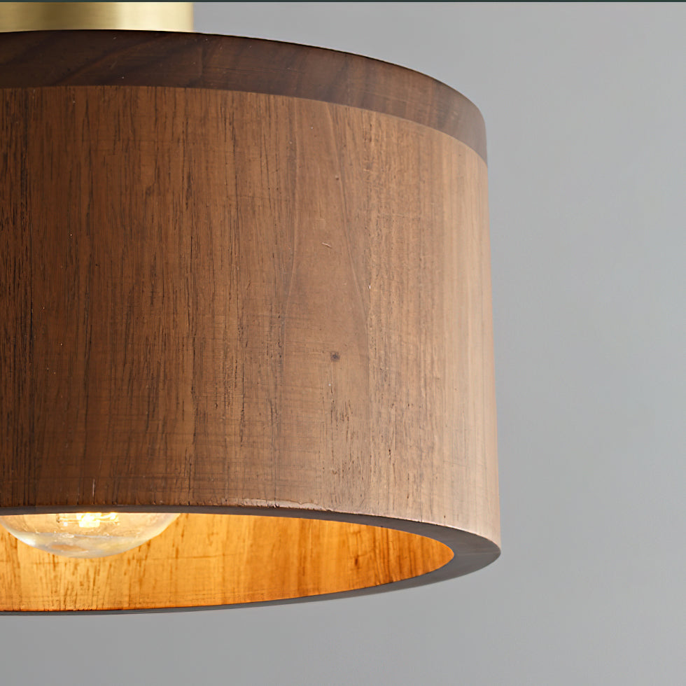 Close view of the walnut grain on this Clérachic pendant, with the bulb glowing and the shade's lit interior golden.