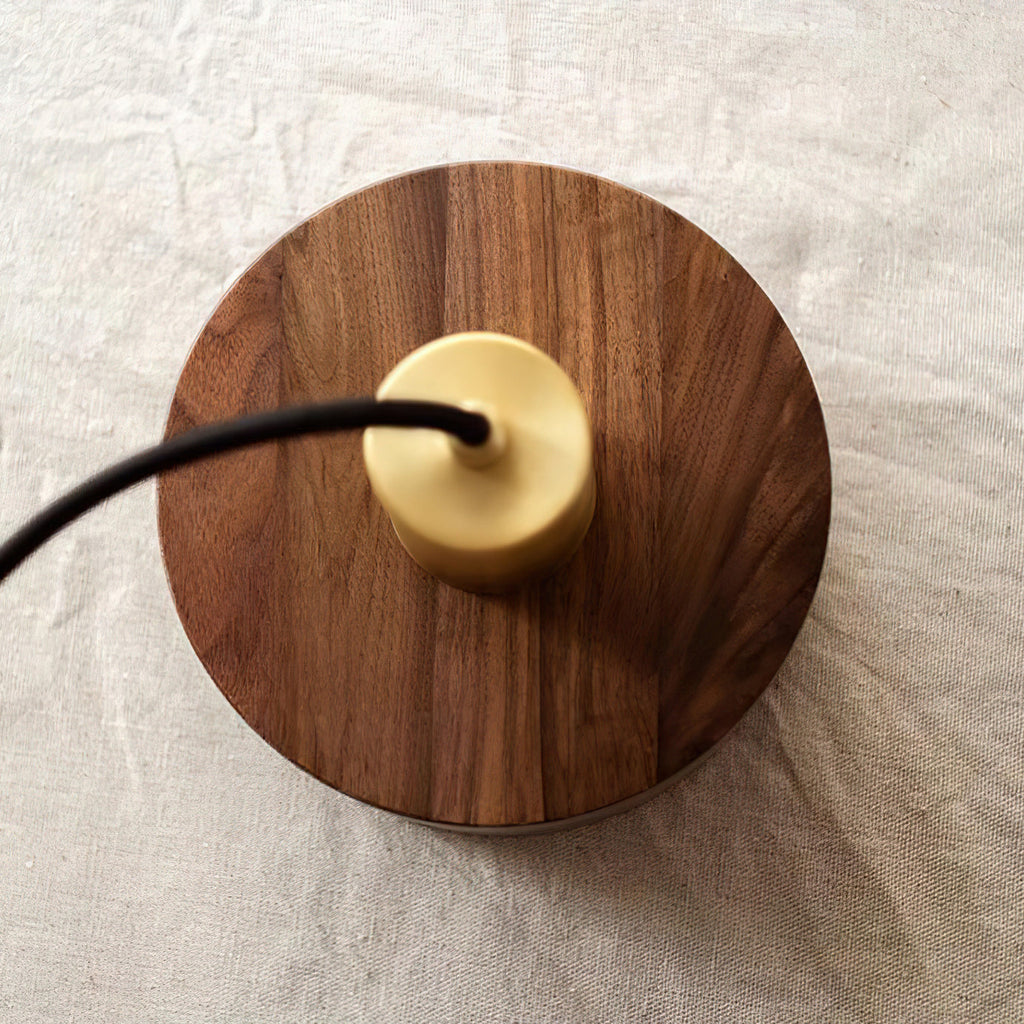 Top view of this Clérachic pendant lying on linen, showing the round walnut top with the brass cap and black cord.