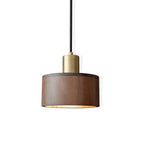 This Clérachic walnut pendant on a white backdrop, lit from within so the inside edge of the shade glows gold.