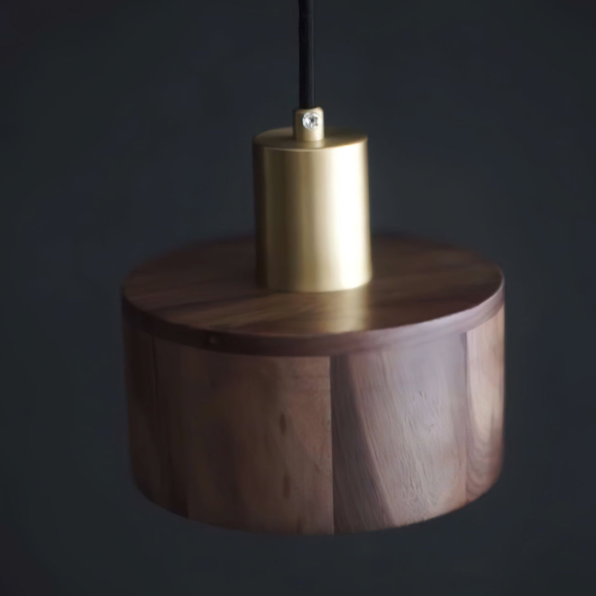 A brass cap above the flat walnut top of this Clérachic pendant, photographed against a dark charcoal backdrop.