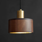 Seen from slightly below, this Clérachic pendant shows its straight walnut sides, a brass cap and a thin line of light at the rim.
