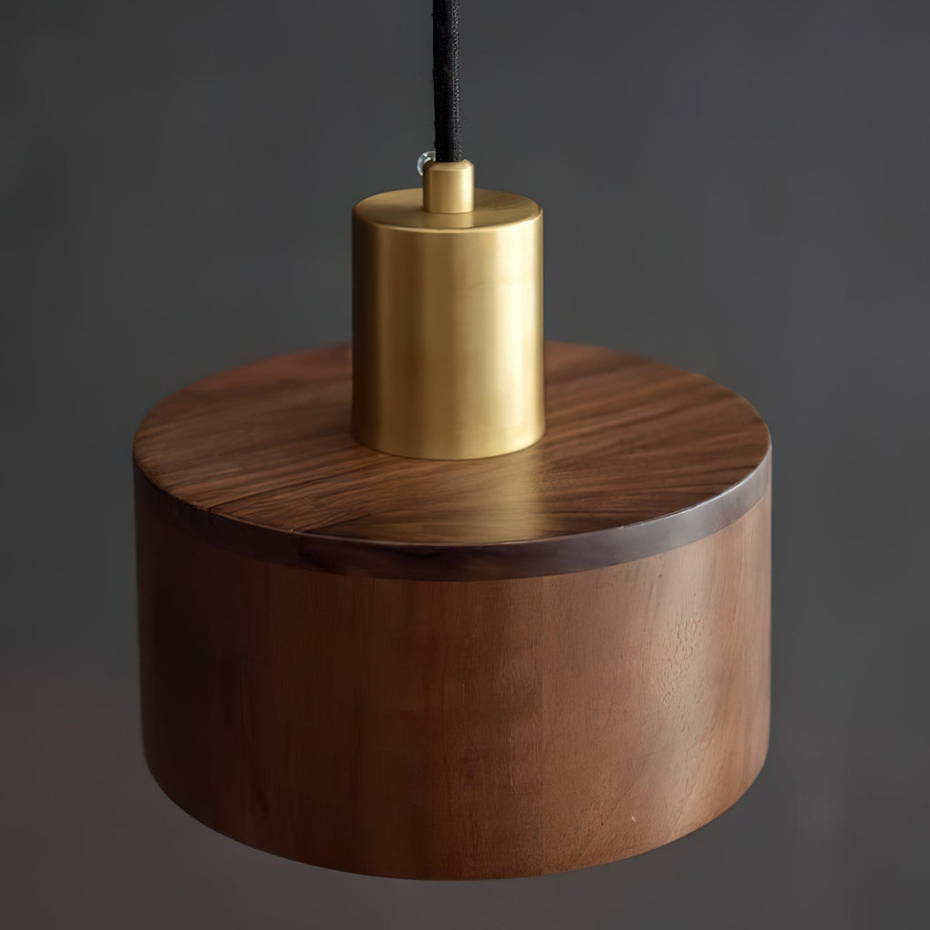 Close, slightly raised view of the brass cap and walnut top of this Clérachic pendant on a dark backdrop.