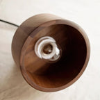 Looking into the shade of this Clérachic pendant on linen, a clear bulb sits at the centre of the walnut interior.