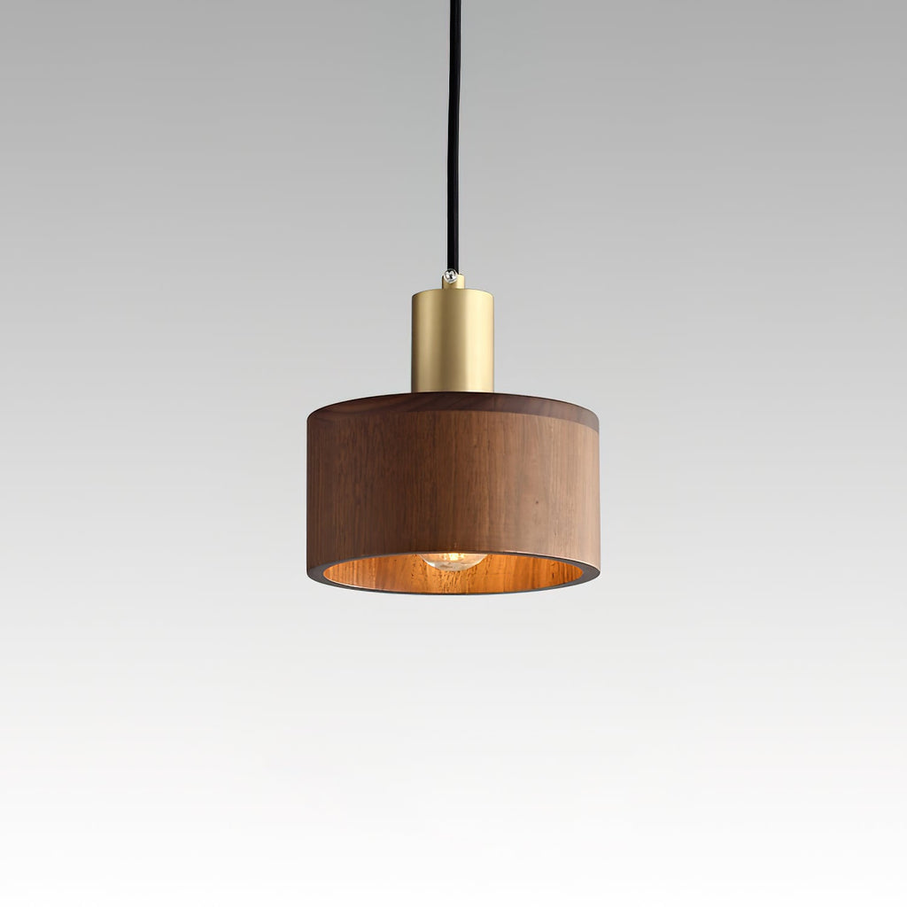 A Clérachic walnut pendant on a pale grey gradient backdrop, the bulb glowing inside the shade beneath a brass cap.