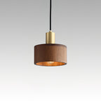 A Clérachic walnut pendant on a pale grey gradient backdrop, the bulb glowing inside the shade beneath a brass cap.