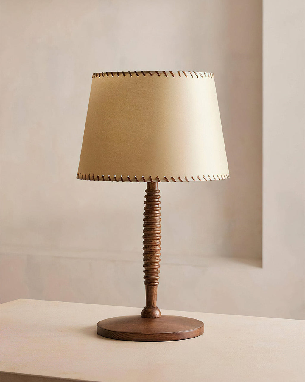 Unlit beige shade with dark edge stitching and a turned walnut-colour stem on this Clérachic table lamp, on a pale surface.