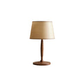 Clérachic table lamp with a beige shade and a ribbed walnut-colour stem on a round base, on a plain white backdrop.