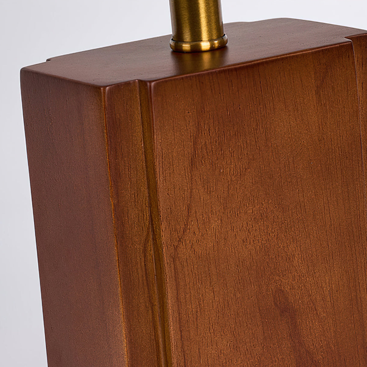 Close view of the walnut grain, rounded edges and brass neck on the block base of this Clérachic table lamp.