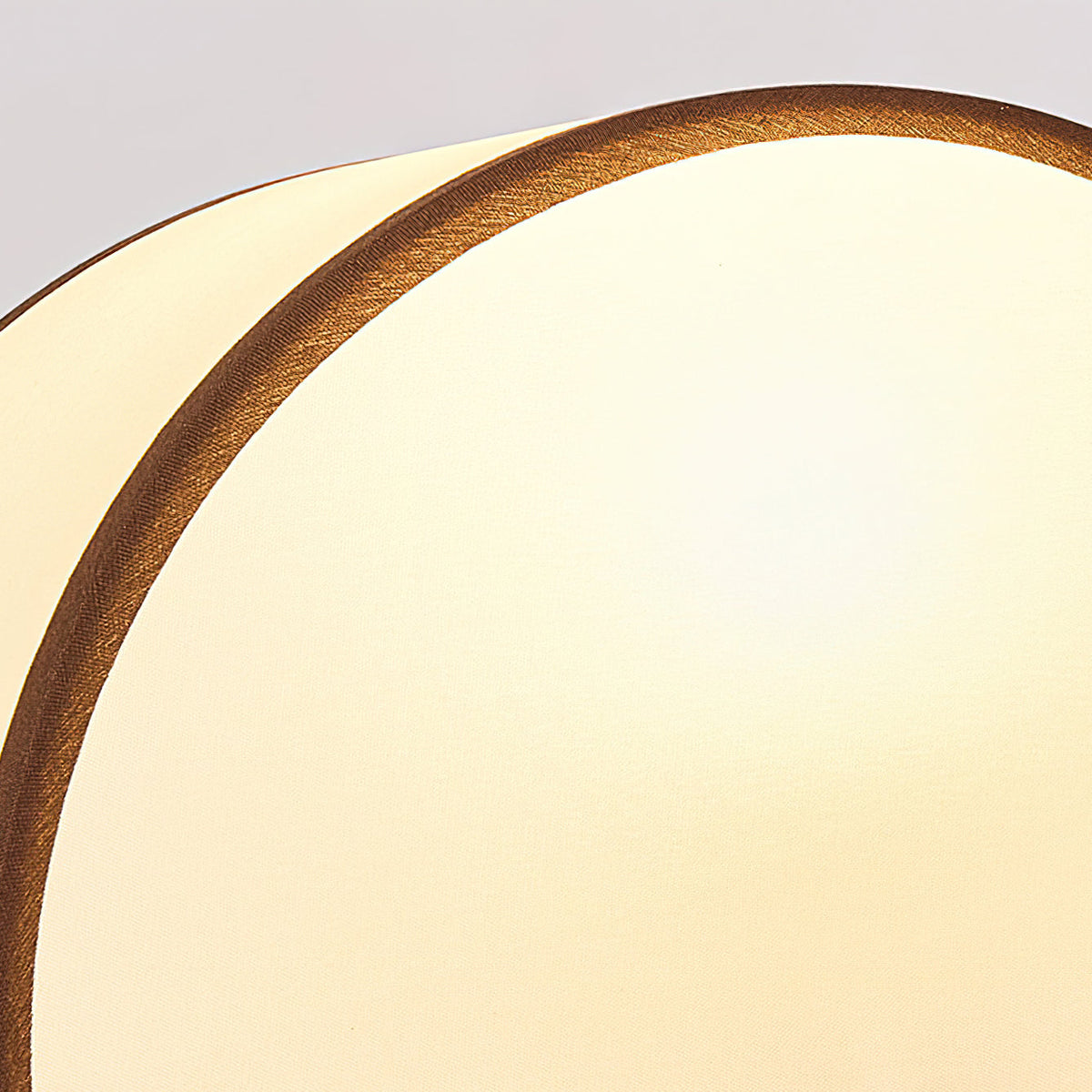 Close view of the half-round white fabric shade and its dark piped edge on this Clérachic table lamp.