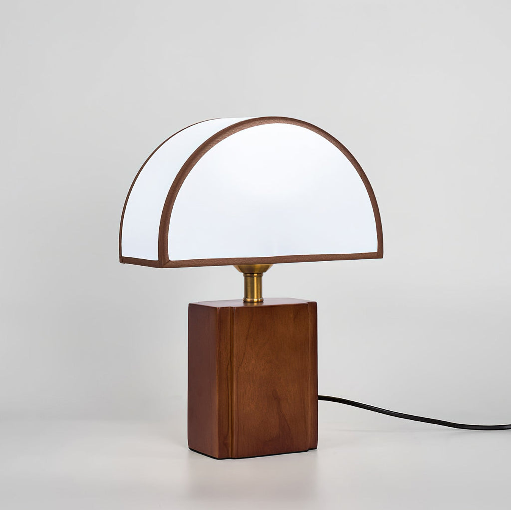 Seen from the front on a pale grey backdrop, a Clérachic table lamp with a half-round white shade and its cord trailing right.