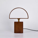 Clérachic table lamp unlit, with its half-round fabric shade open at the front, on a pale grey backdrop.