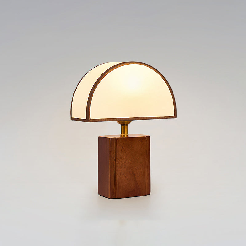 Clérachic walnut and white table lamp, lit, on a soft grey backdrop with a half-round fabric shade.