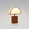 Clérachic walnut and white table lamp, lit, on a soft grey backdrop with a half-round fabric shade.