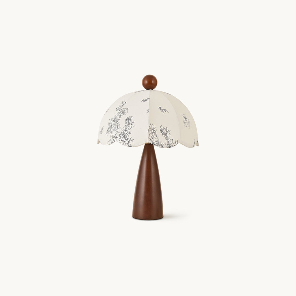 This Clérachic table lamp on a plain white backdrop, with a tapered walnut-tone wooden base and a scalloped floral-print shade.