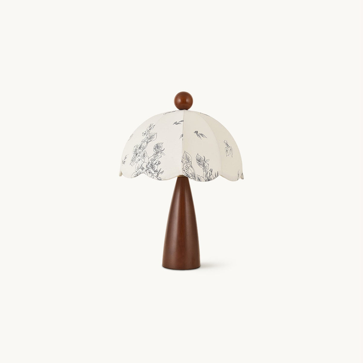 This Clérachic table lamp on a plain white backdrop, with a tapered walnut-tone wooden base and a scalloped floral-print shade.