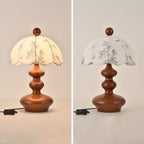 Two views of this Clérachic lamp with a rounded, tiered wooden base, lit and unlit, with its cord and switch to the left.