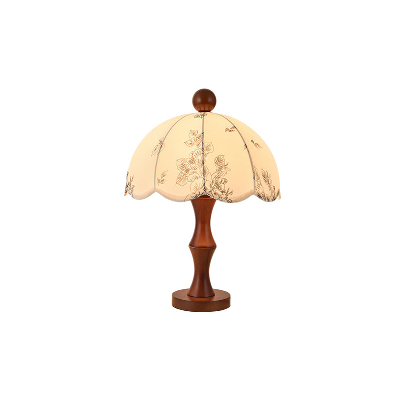 This Clérachic table lamp with a waisted wooden base on a round foot and a scalloped floral shade, on a white background.
