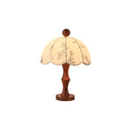 This Clérachic table lamp with a waisted wooden base on a round foot and a scalloped floral shade, on a white background.