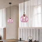 Two pink Clérachic water ripple glass globe pendants at different drops above a dining nook, the dimpled glass lit soft against linen curtains.