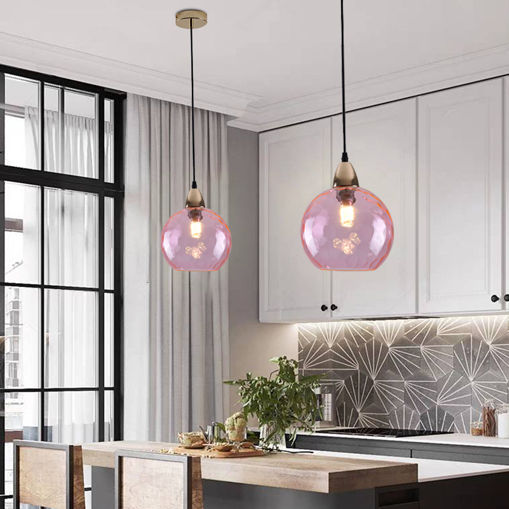 Pink Clérachic water ripple glass globe pendants hung in a white kitchen, a gold ceiling rose above each dimpled globe.