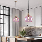 Pink Clérachic water ripple glass globe pendants hung in a white kitchen, a gold ceiling rose above each dimpled globe.
