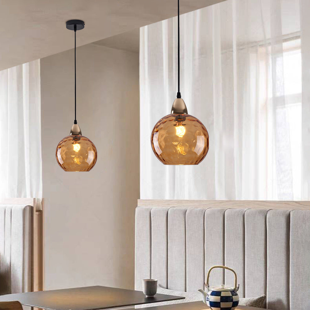 Orange Clérachic water ripple glass globe pendants over a banquette seat, the moulded dimples reading warm brown against pale plaster.