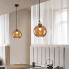 Orange Clérachic water ripple glass globe pendants over a banquette seat, the moulded dimples reading warm brown against pale plaster.
