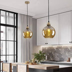Two amber Clérachic water ripple glass globe pendants lighting a white kitchen, dimpled glass over the worktop and dining table.