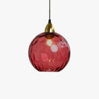 Single crimson Clérachic water ripple glass globe pendant on a white studio ground, its dimpled surface lit from within.