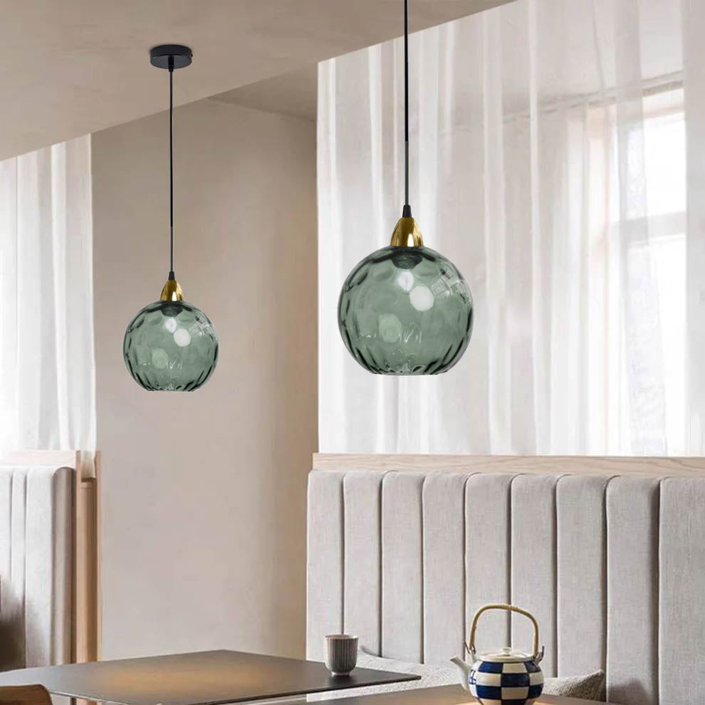 Dark green Clérachic water ripple glass globe pendants hung in pairs over a dining nook, the tinted glass reading almost slate in daylight.