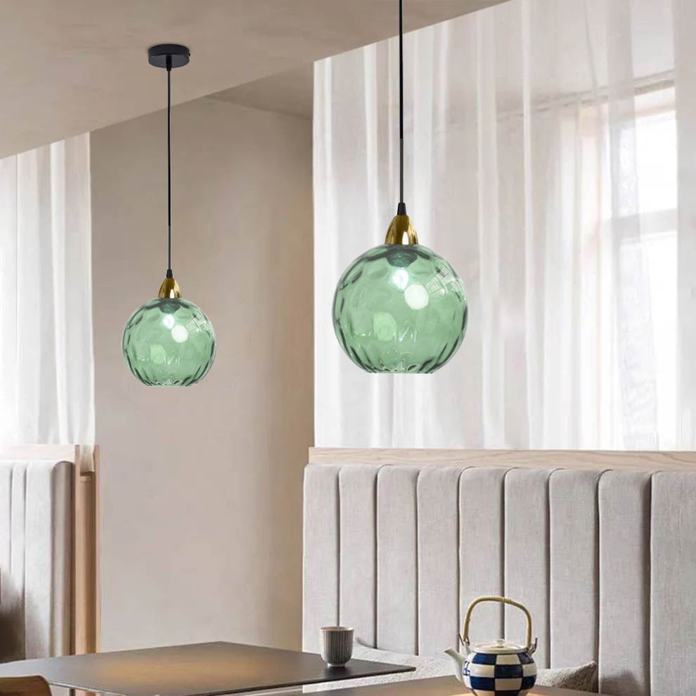 Light green Clérachic water ripple glass globe pendants beside a linen curtain, the moulded dimples scattering the light.